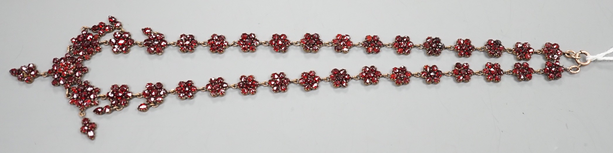 A late Victorian gilt and yellow metal, garnet cluster set drop necklace, 48cm.